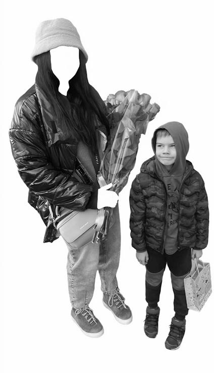 black and white image of a woman and a boy standing together. The woman holds flowers - her face and hands have been cut out of the photo so only her clothes and hair are visible