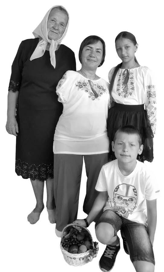 black and white image of an older woman, a younger woman and a girl standing together with a boy crouched down in front of them holding a basket