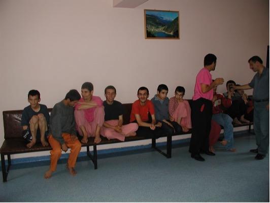 children and young adults sit on couches up against a wall