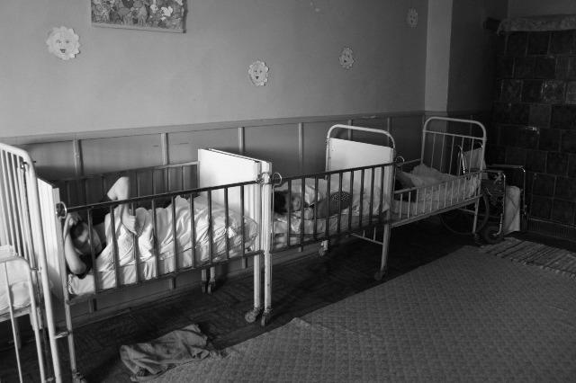 children in cribs lined up against a wall