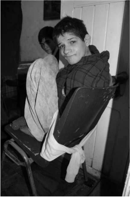 a boy tied to a chair with cloth restraints
